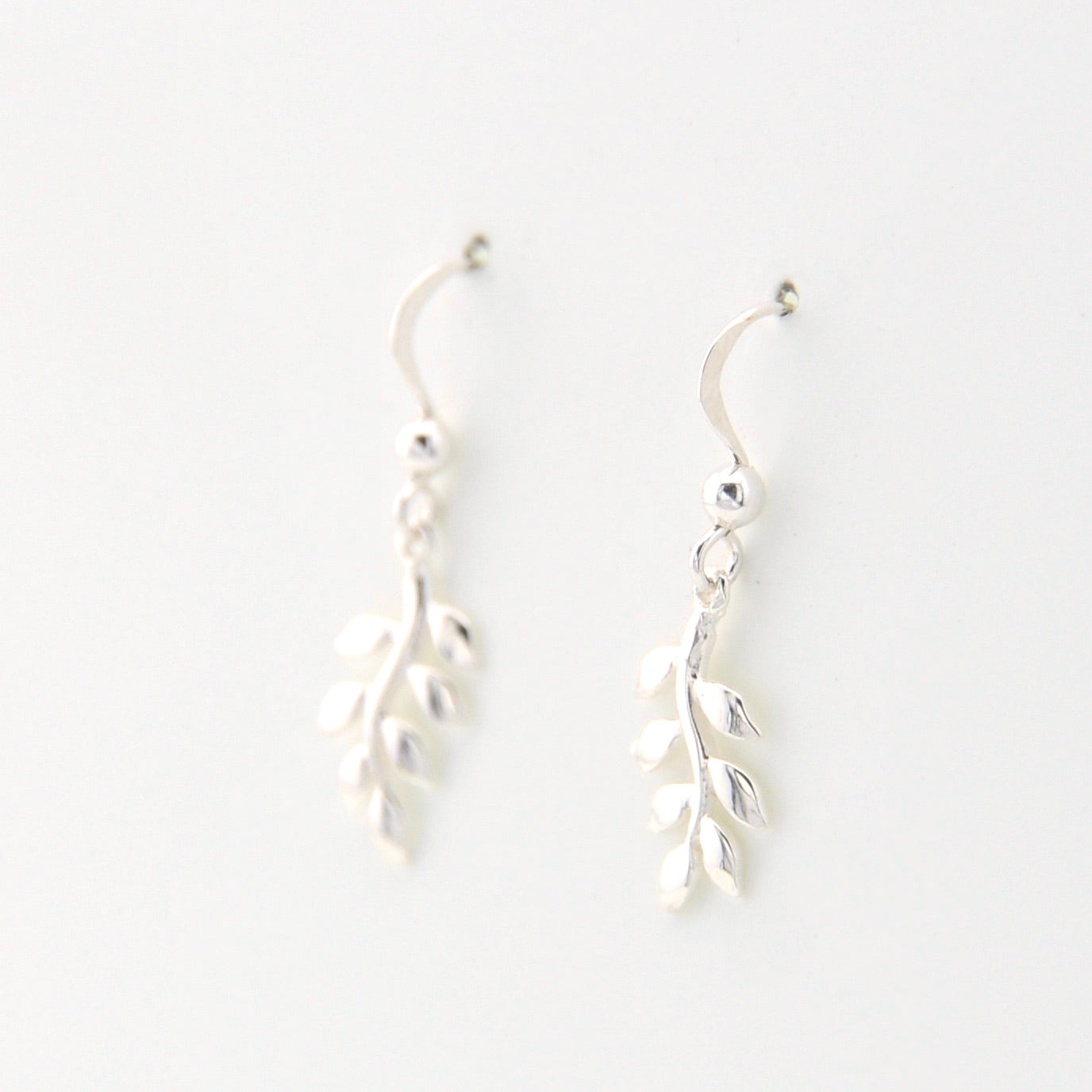 Silver leaf-shaped earrings on a white background