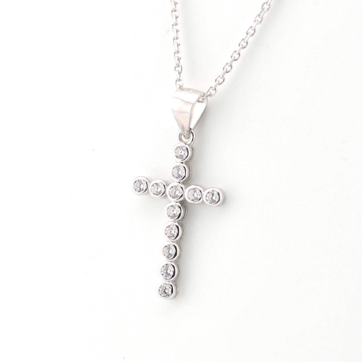 Silver cross pendant necklace with clear stones on a white background