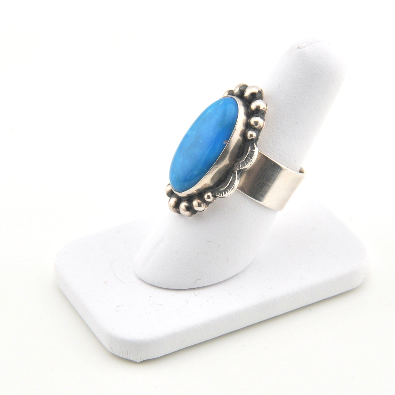 Silver ring with a blue stone on a white stand