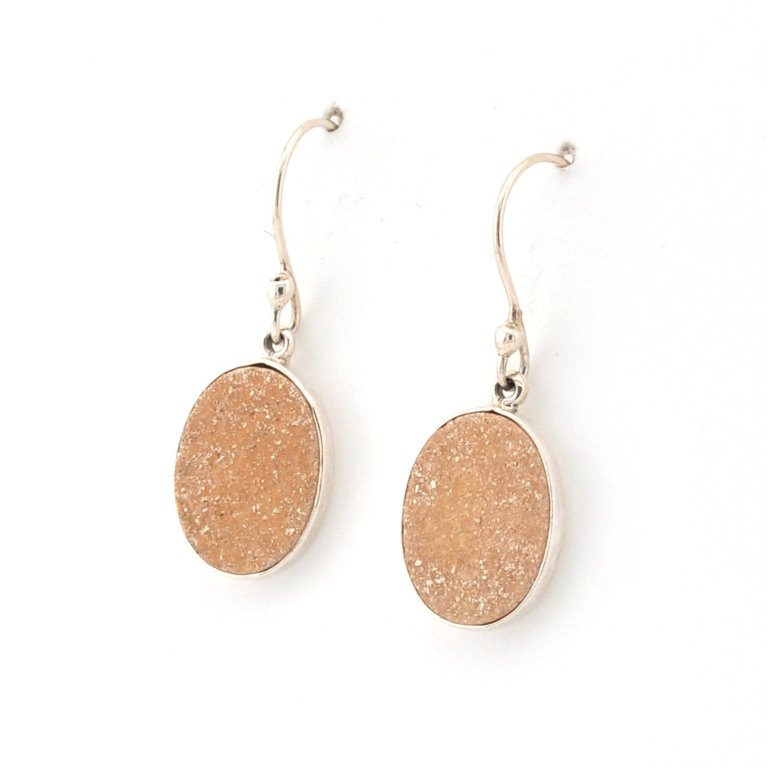 Pair of gold glittery oval earrings on a white background
