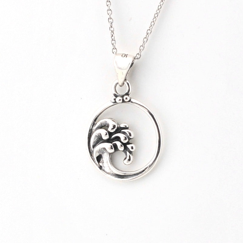 Silver necklace with a circular pendant featuring wave design on a white background