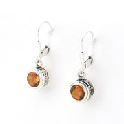 Pair of silver earrings with round amber stones on a white background