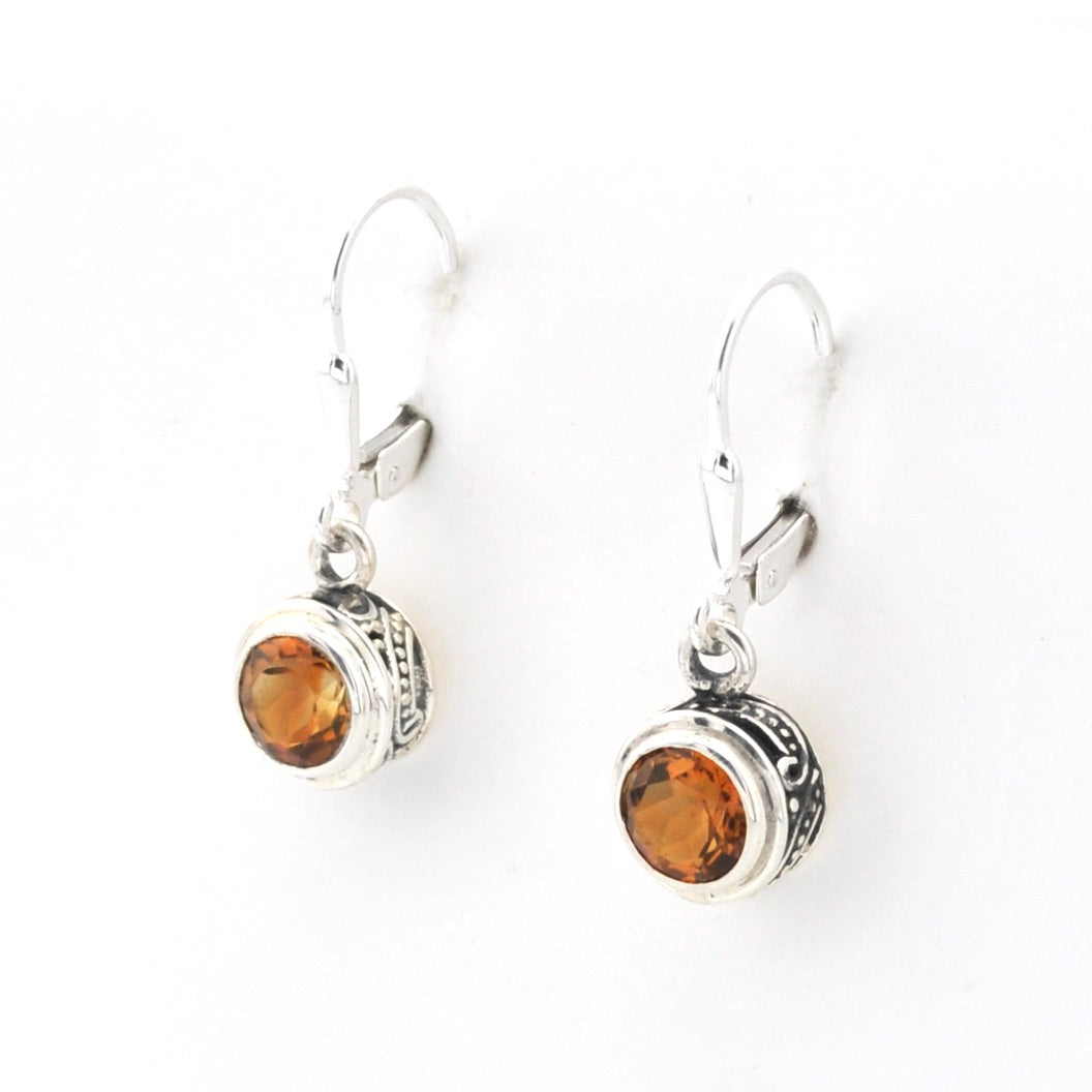 Pair of silver earrings with round amber stones on a white background