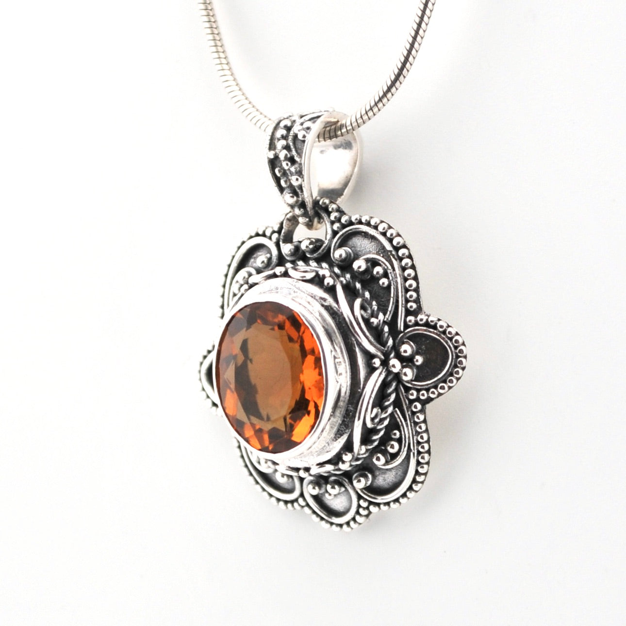 Silver pendant with an orange gemstone on a white background