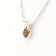 Marquise-shaped pendant with a brown gemstone on a white background