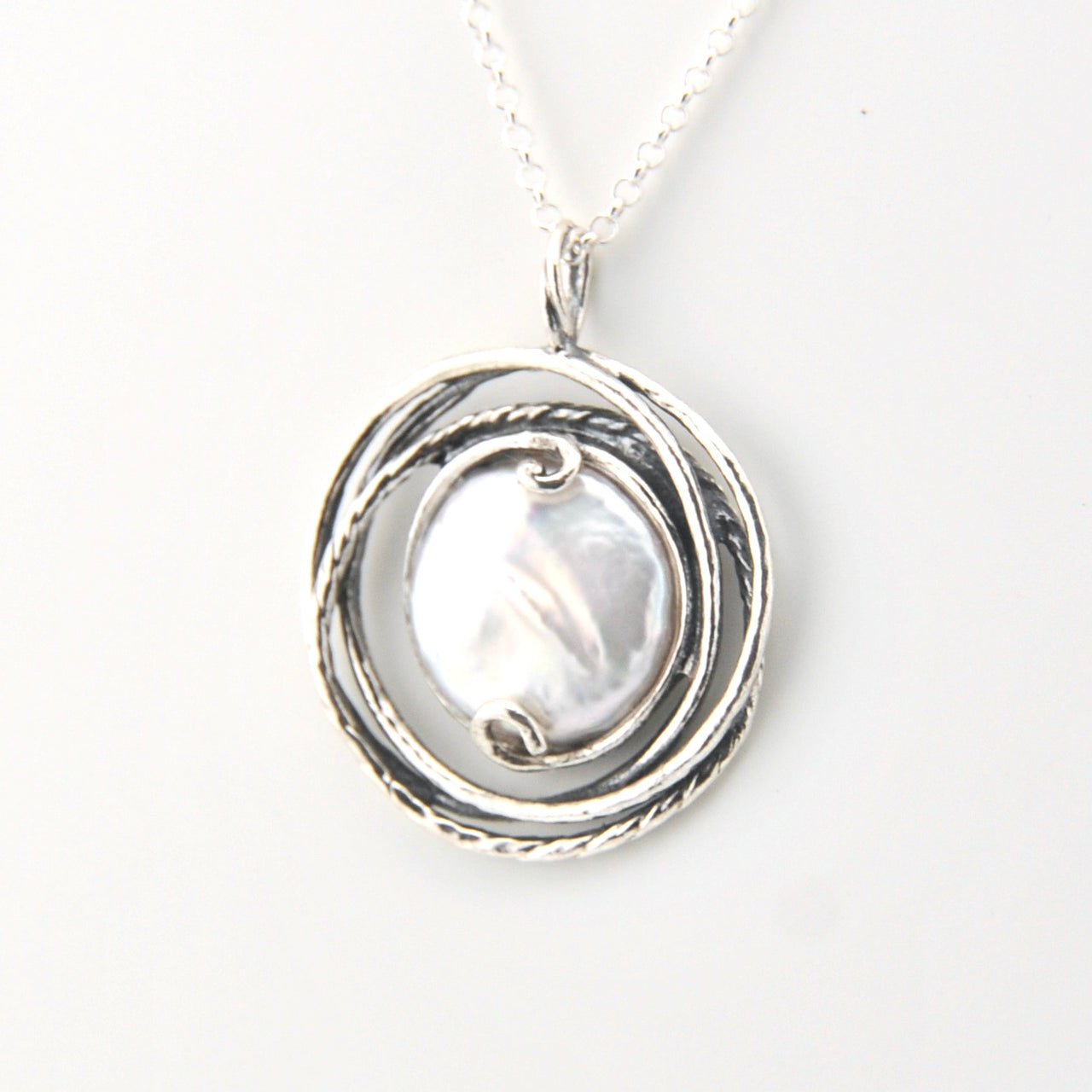 Silver pendant with a central pearl on a white background
