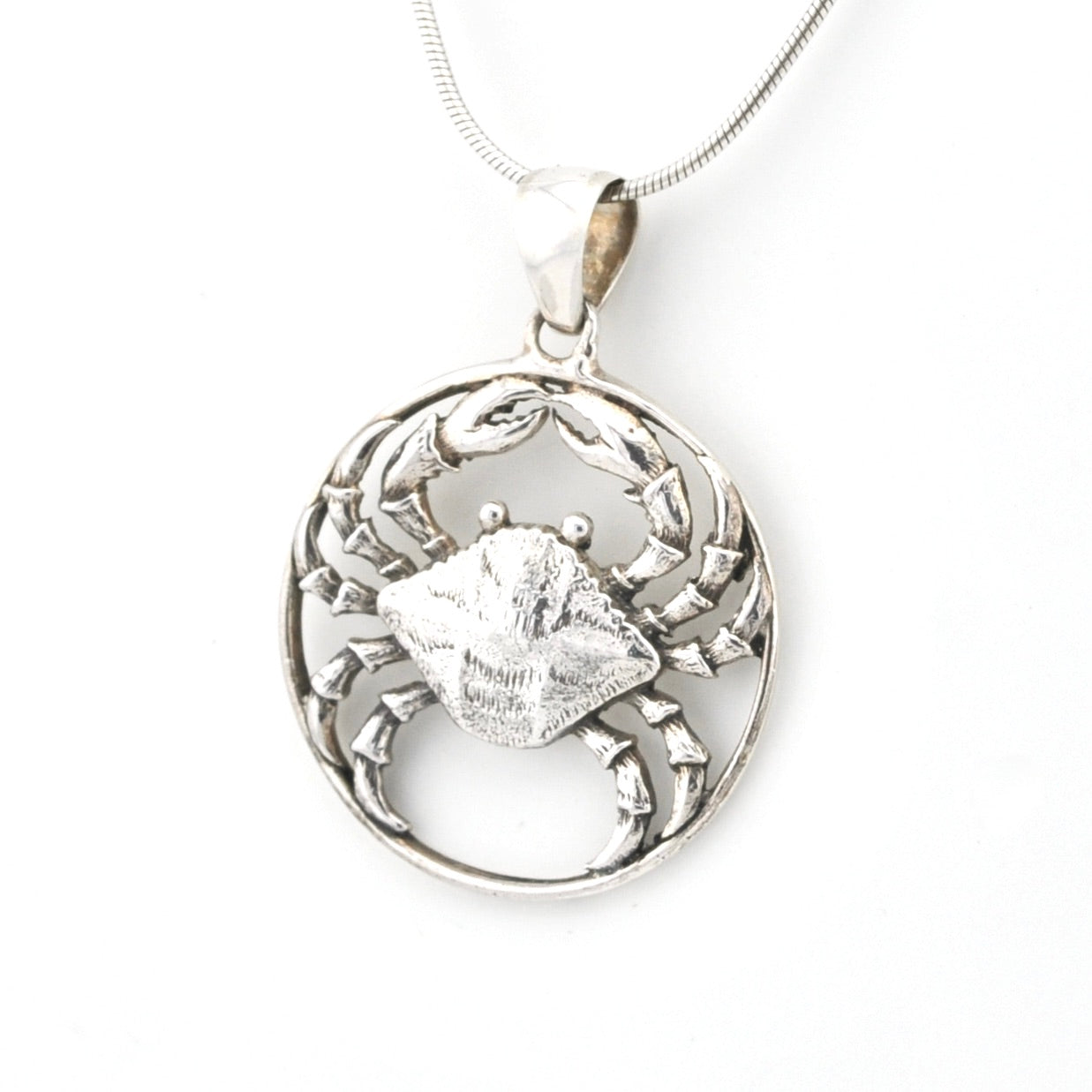 Silver pendant with a crab design on a white background