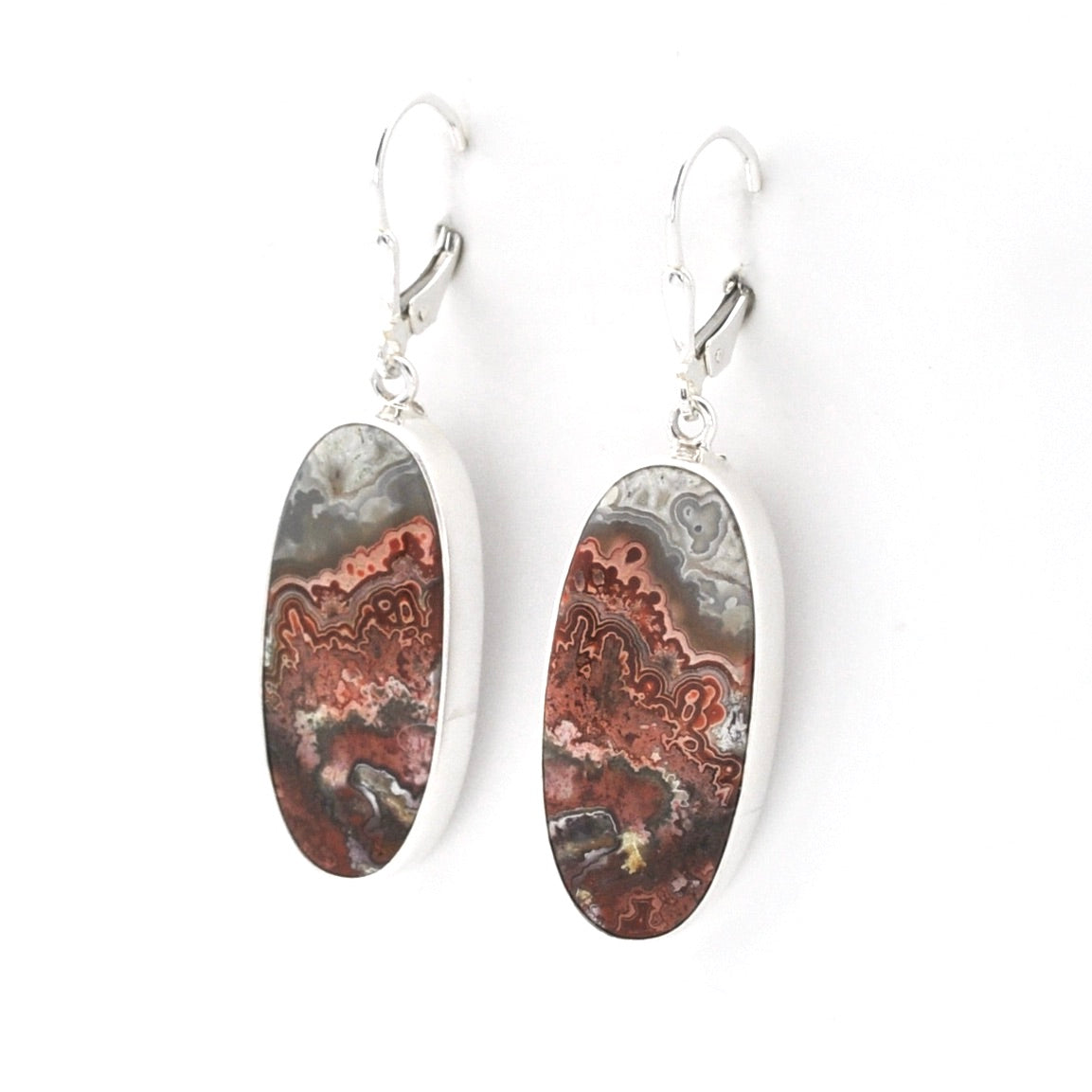 A pair of silver drop earrings featuring oval-shaped dalmatian agate stone pendants with natural brown, gray, and white agate patterns, suspended from silver leverback hooks on a white background.