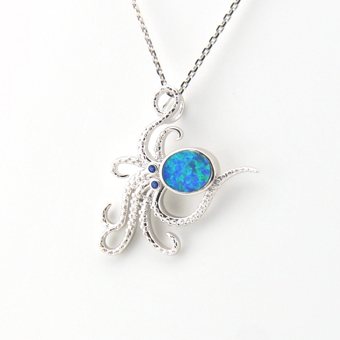 Silver pendant with a blue opal stone on a white background