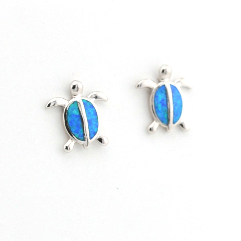 Turtle-shaped earrings with blue opal inlay on a white background