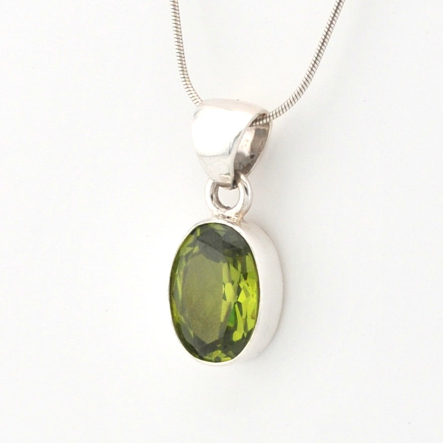 Silver pendant with a green gemstone on a white background