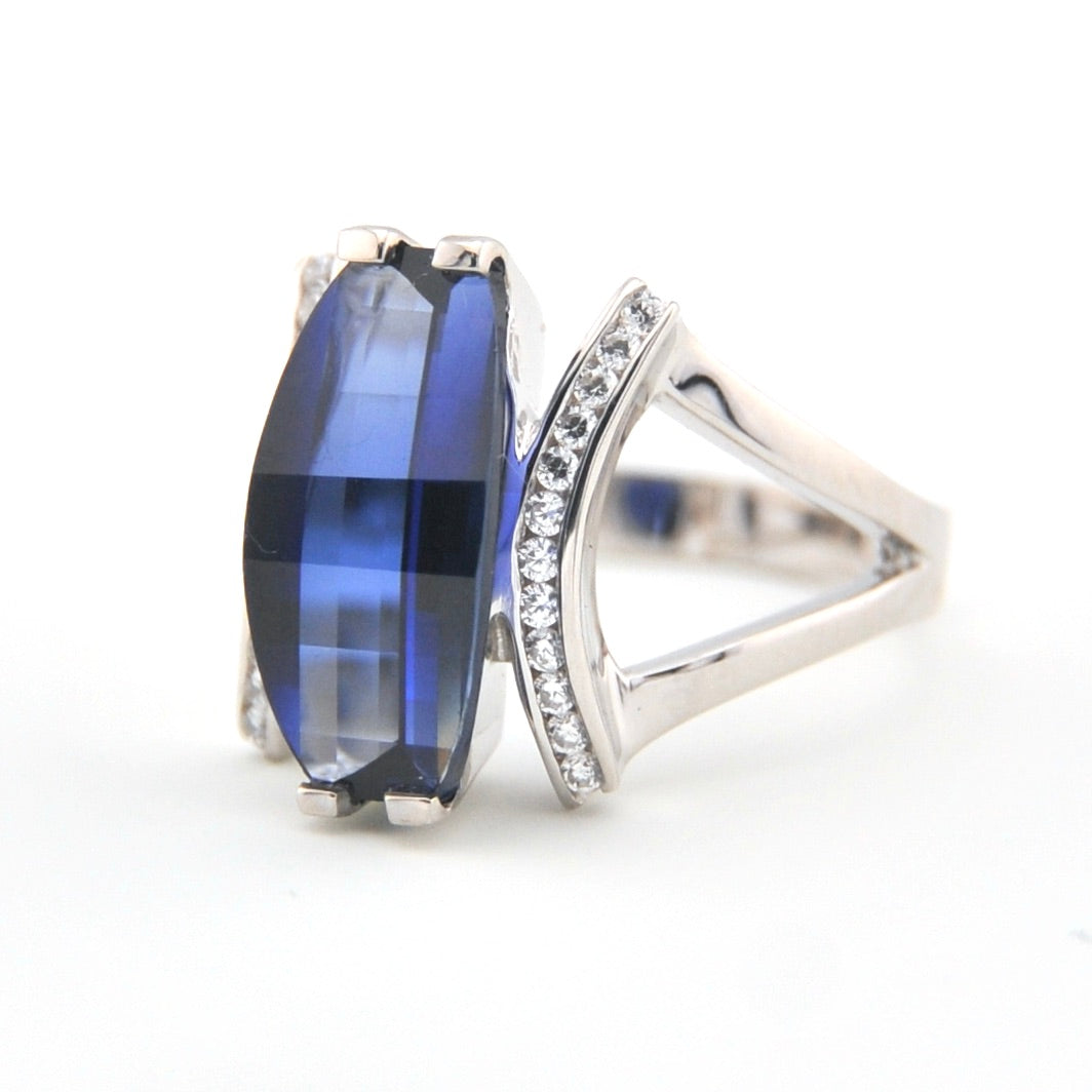 Silver ring with a blue gemstone and diamond accents on a white background