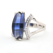 Silver ring with a blue gemstone and diamond accents on a white background