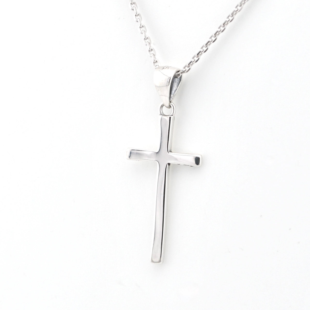Silver cross pendant on a chain against a white background