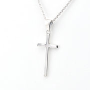 Silver cross pendant on a chain against a white background