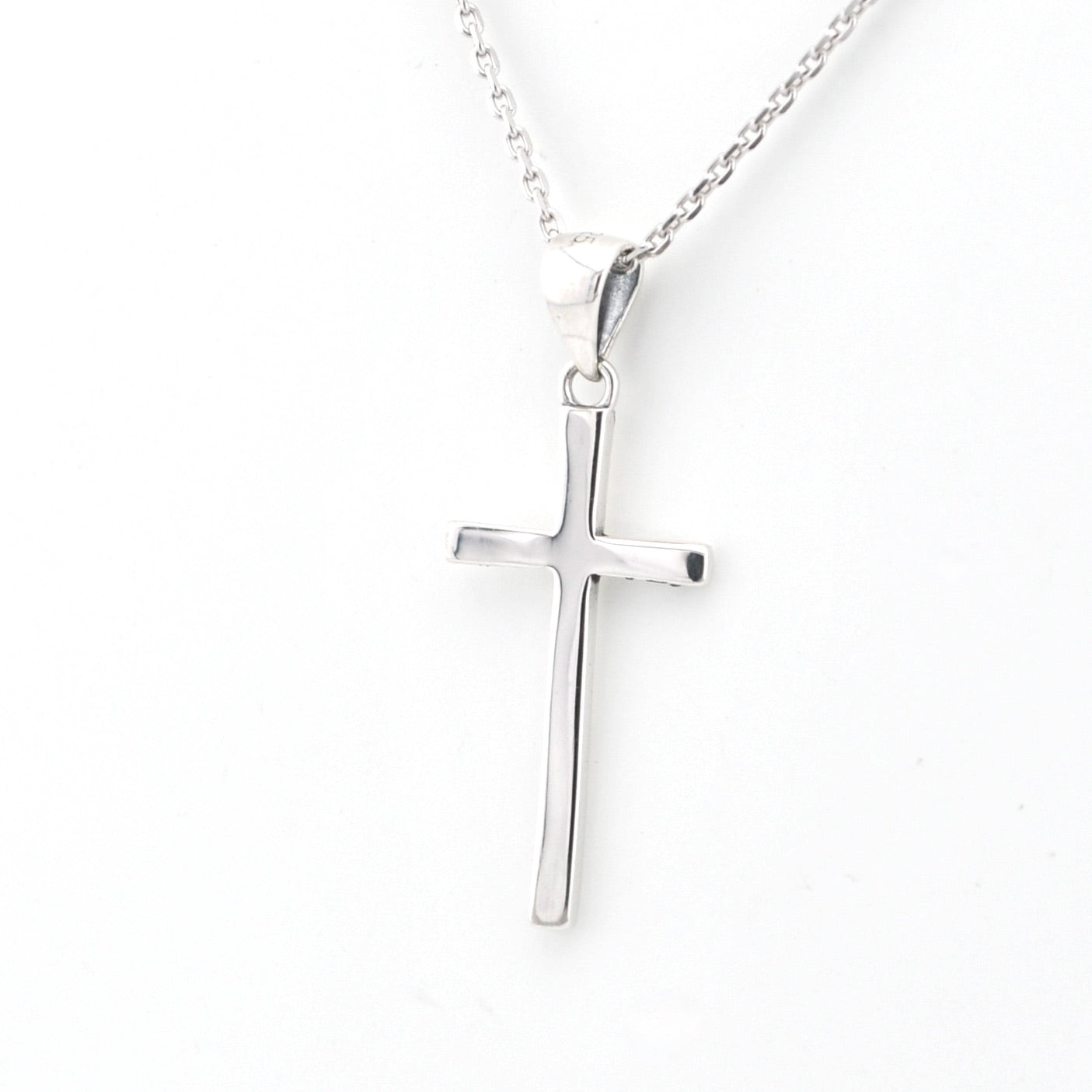 Silver cross pendant on a chain against a white background