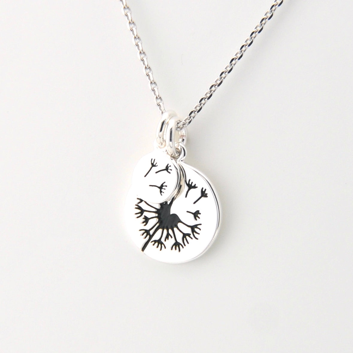 Silver necklace with a pendant featuring a black leaf design on a white background