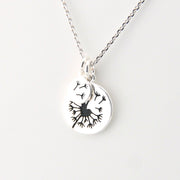 Silver necklace with a pendant featuring a black leaf design on a white background