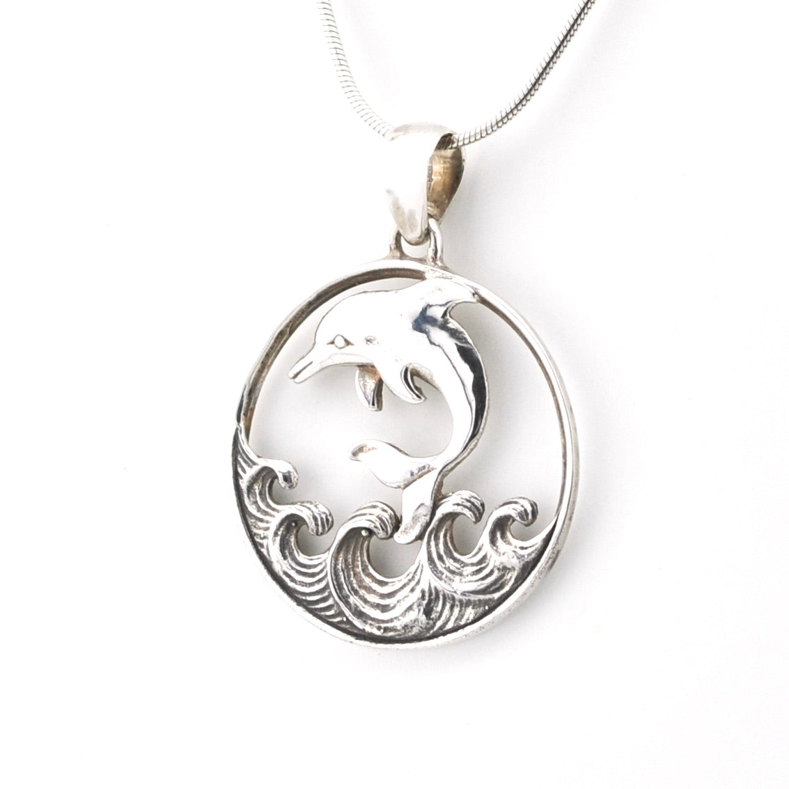 Silver pendant with dolphin design on a white background