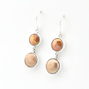 Pair of earrings with round, multicolored stones on a white background