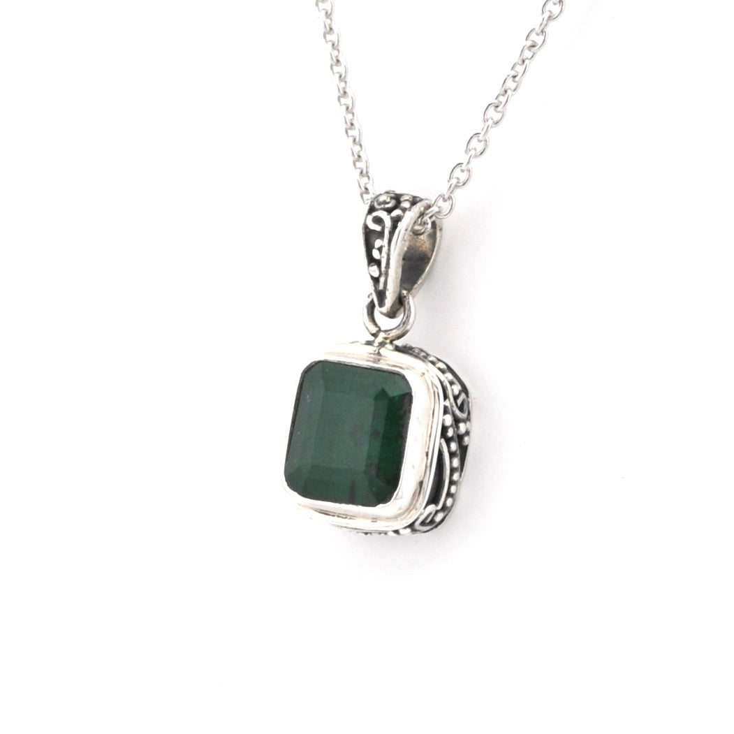 Silver pendant with a green stone on a white background