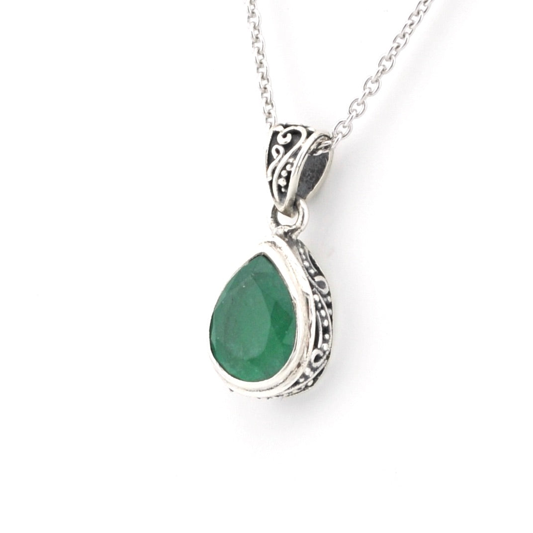 Silver pendant with a green gemstone on a white background
