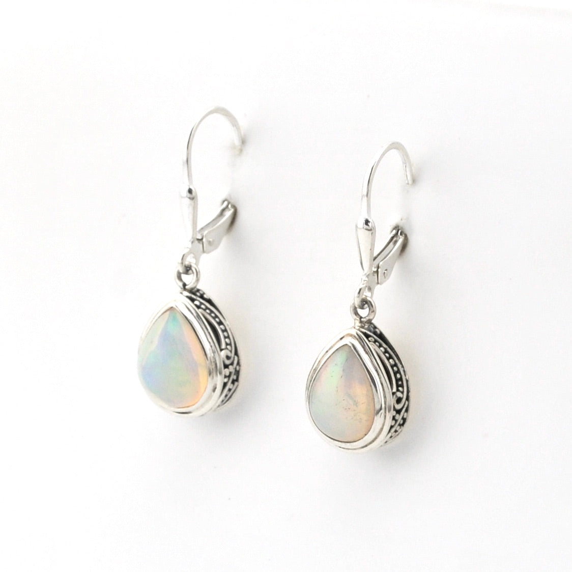 Pair of silver earrings with opal stones on a white background