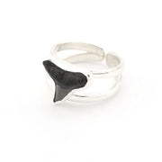 Silver ring with a black shark tooth design on a white background