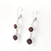 A pair of silver leverback dangle earrings featuring two small square bezel-set dark red garnet stones, shown against a plain white background.