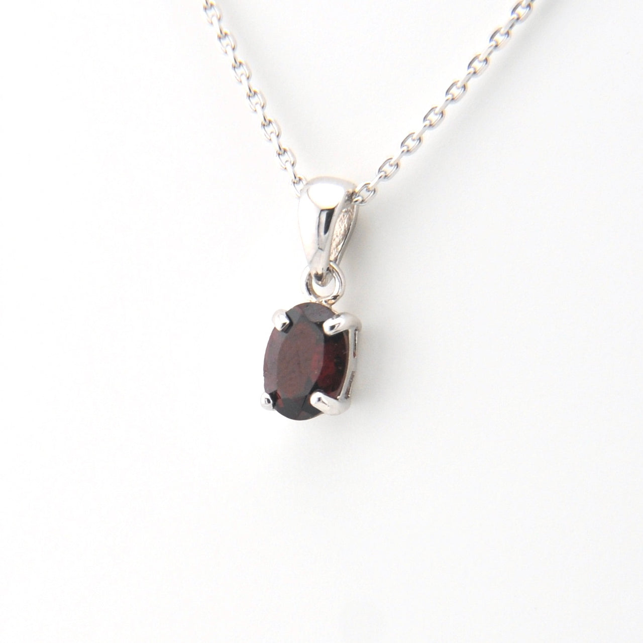 Silver necklace with a garnet pendant on a white background