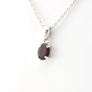 Silver necklace with a garnet pendant on a white background