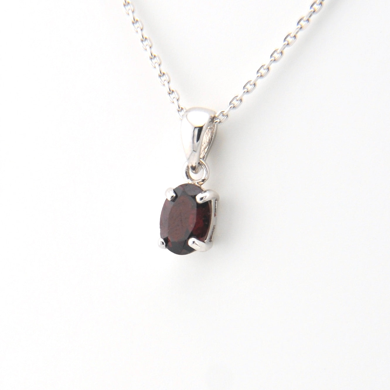 Silver necklace with a garnet pendant on a white background