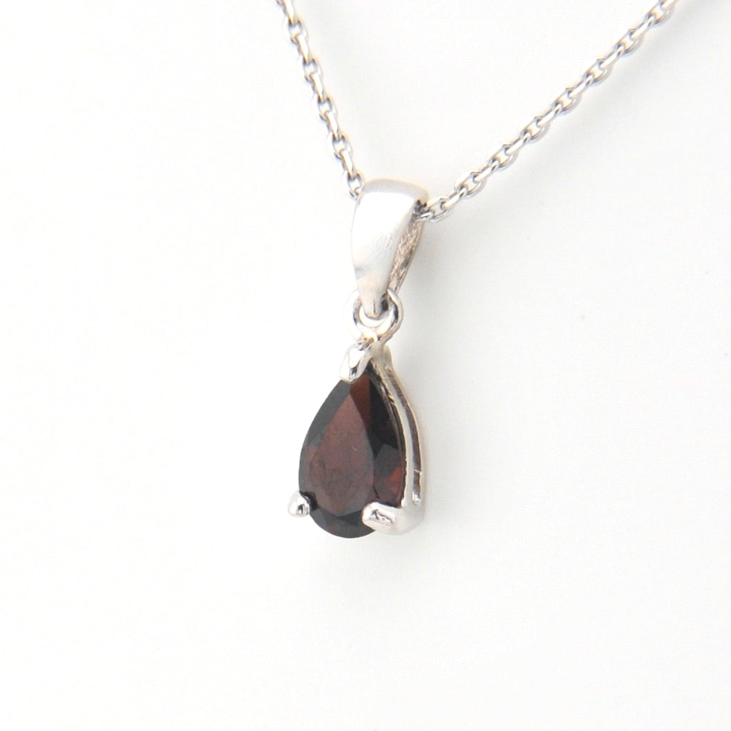 Teardrop-shaped gemstone pendant on a silver chain against a white background