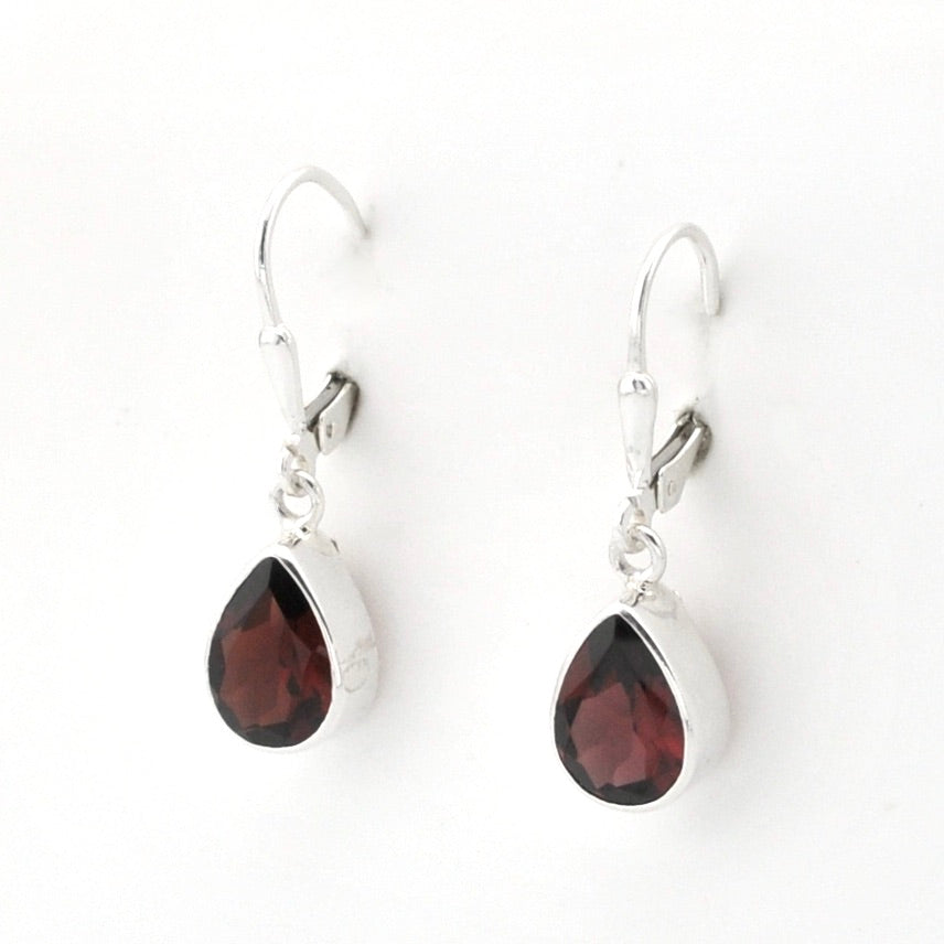 A pair of silver leverback drop earrings featuring teardrop-shaped dark red garnet gemstones in polished silver bezel settings, shown on a plain white background.