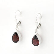 A pair of silver leverback drop earrings featuring teardrop-shaped dark red garnet gemstones in polished silver bezel settings, shown on a plain white background.