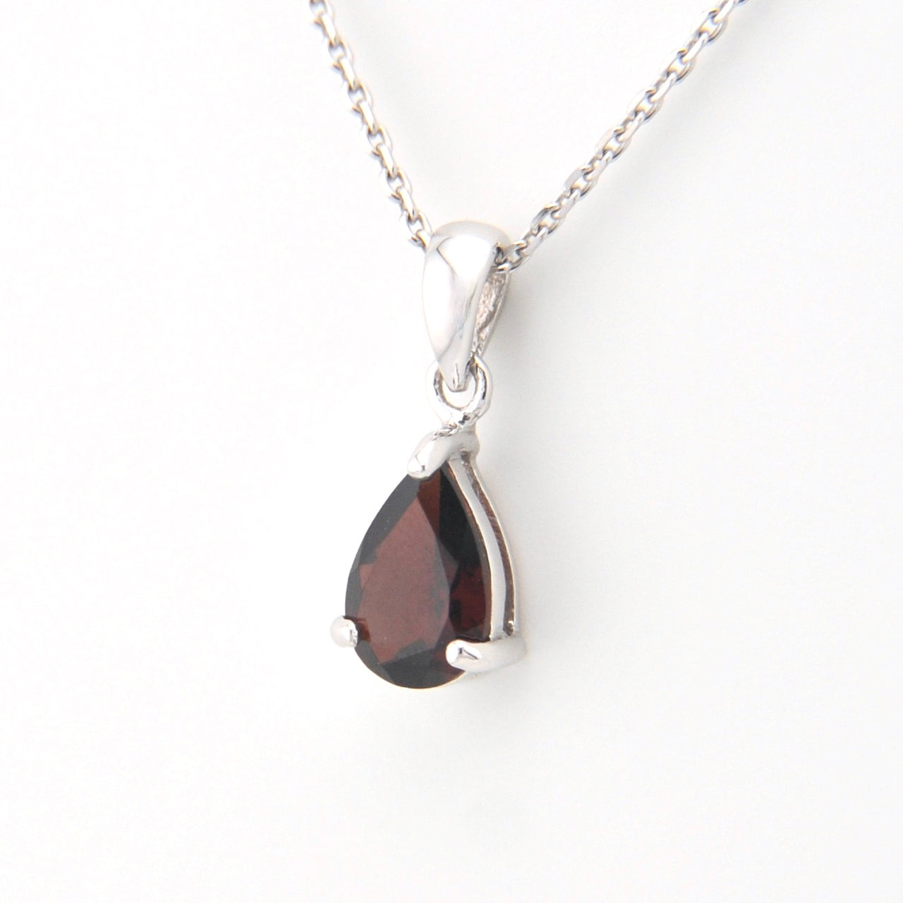 Teardrop-shaped pendant with a red gemstone on a white background