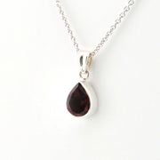 Teardrop-shaped gemstone pendant on a silver chain against a white background