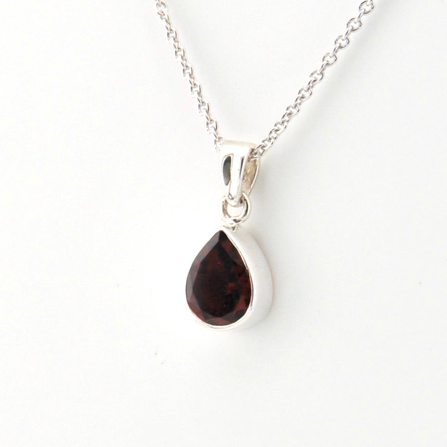 Teardrop-shaped gemstone pendant on a silver chain against a white background
