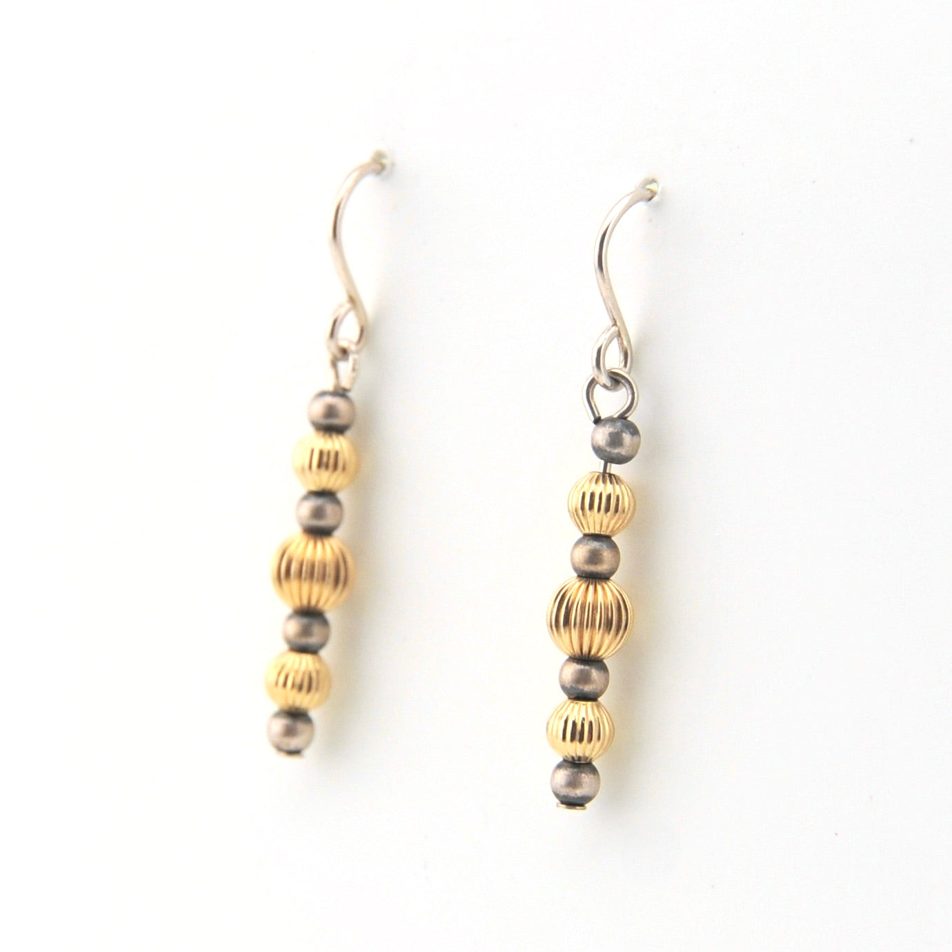 Pair of earrings with gold and silver beads on a white background