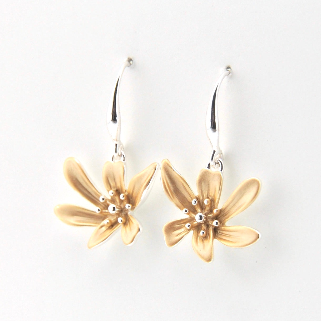 Gold flower-shaped earrings on a white background