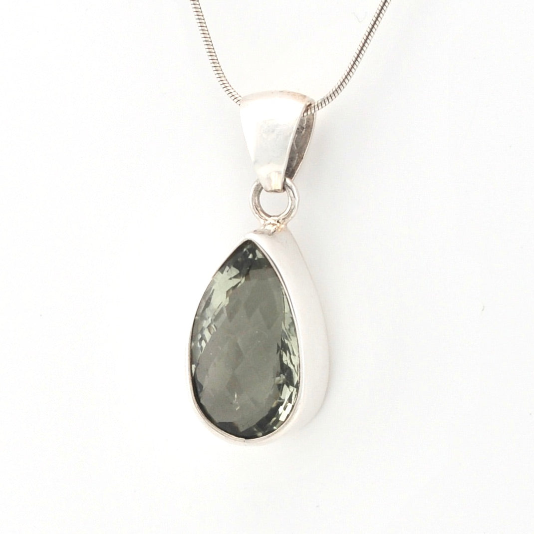 Teardrop-shaped pendant with a green gemstone on a white background