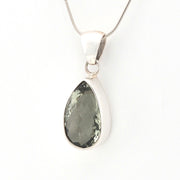 Teardrop-shaped pendant with a green gemstone on a white background