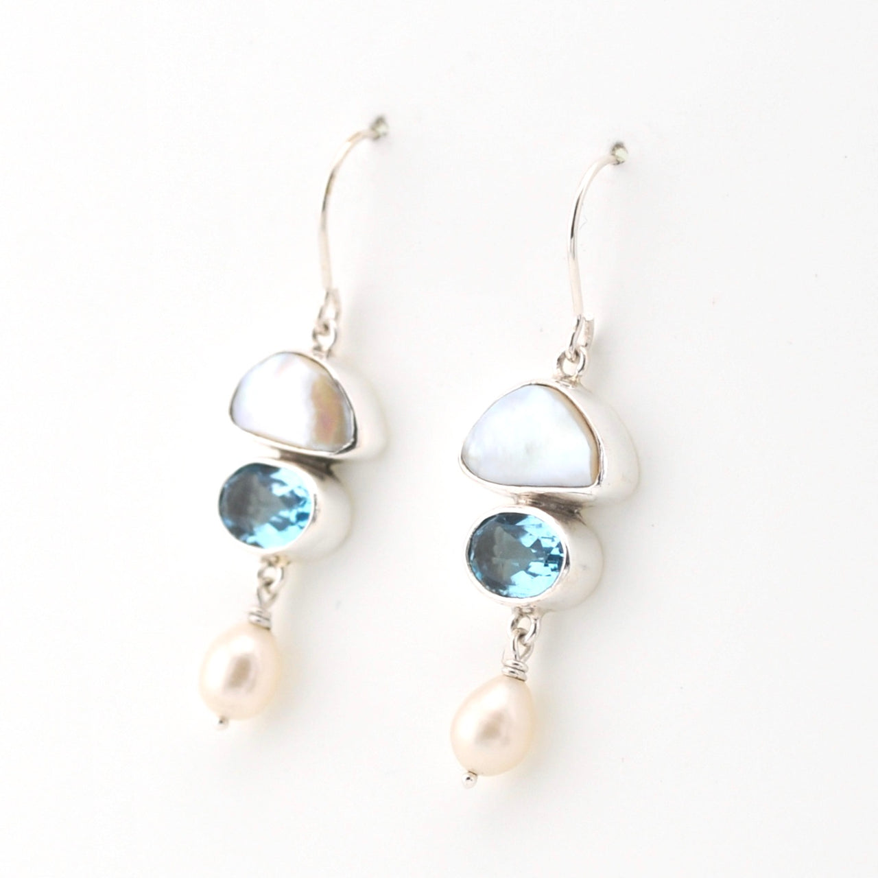 Silver earrings with blue gemstones and pearls on a white background