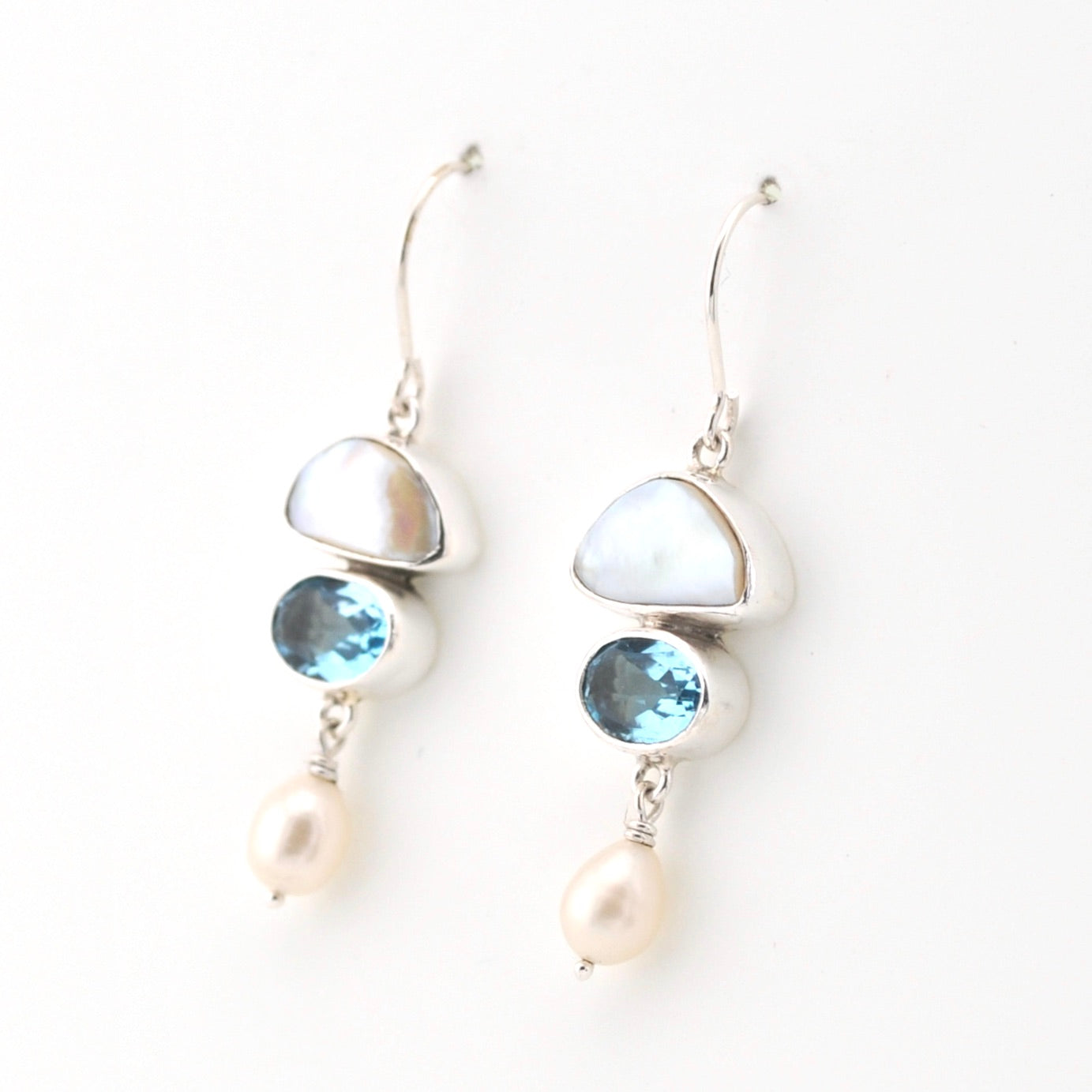 Silver earrings with blue gemstones and pearls on a white background