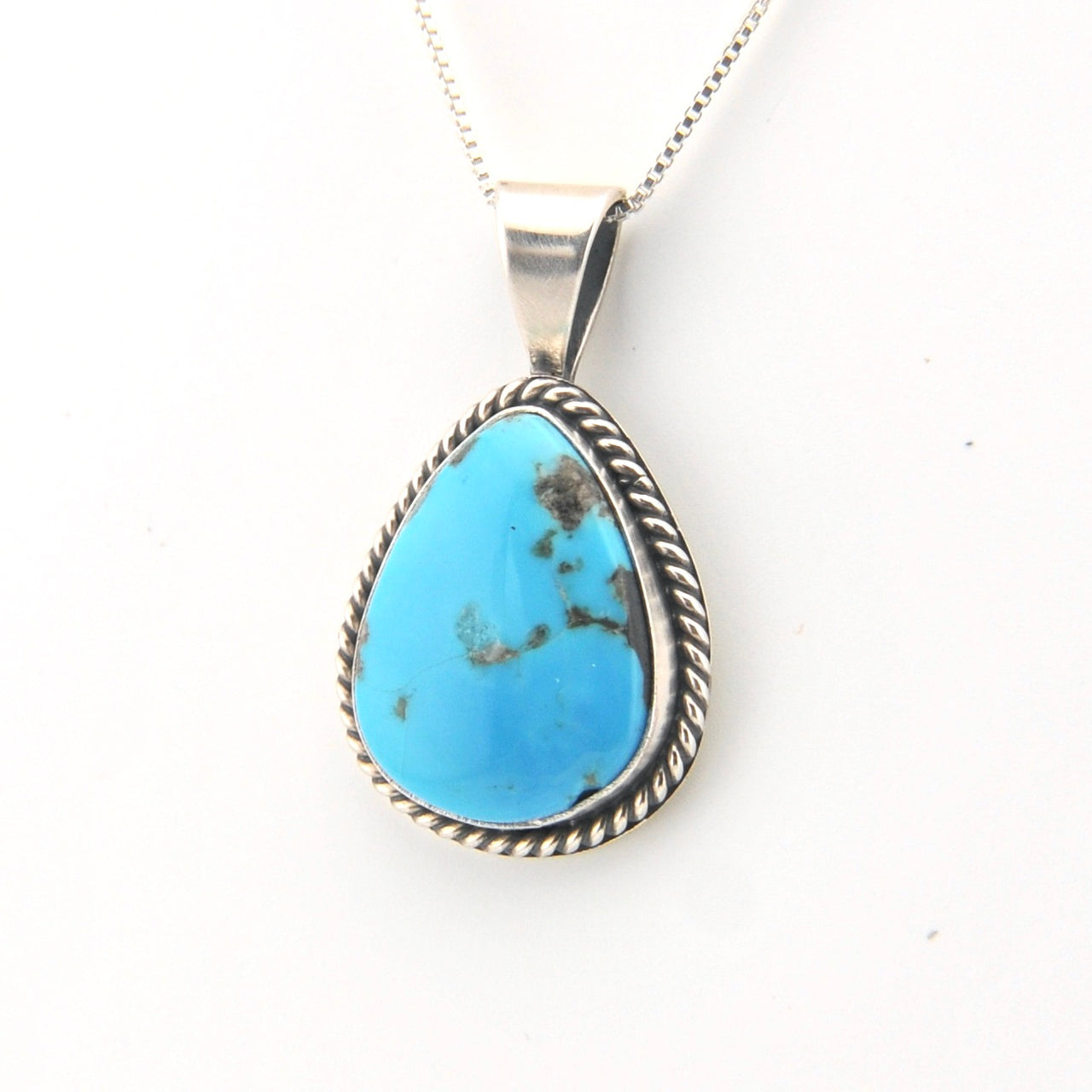 Turquoise pendant on a silver chain against a white background