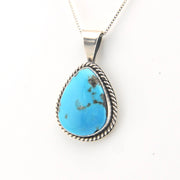 Turquoise pendant on a silver chain against a white background
