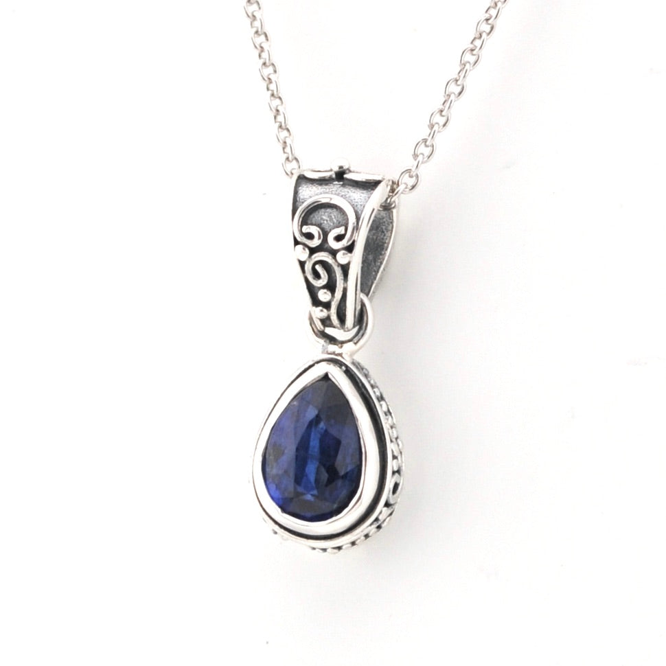 Silver pendant with a blue gemstone on a white background