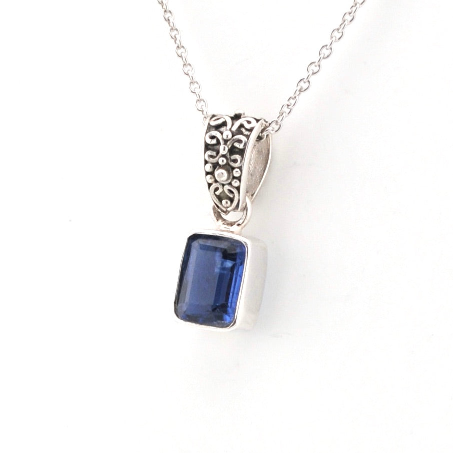 Silver pendant with a blue gemstone on a white background