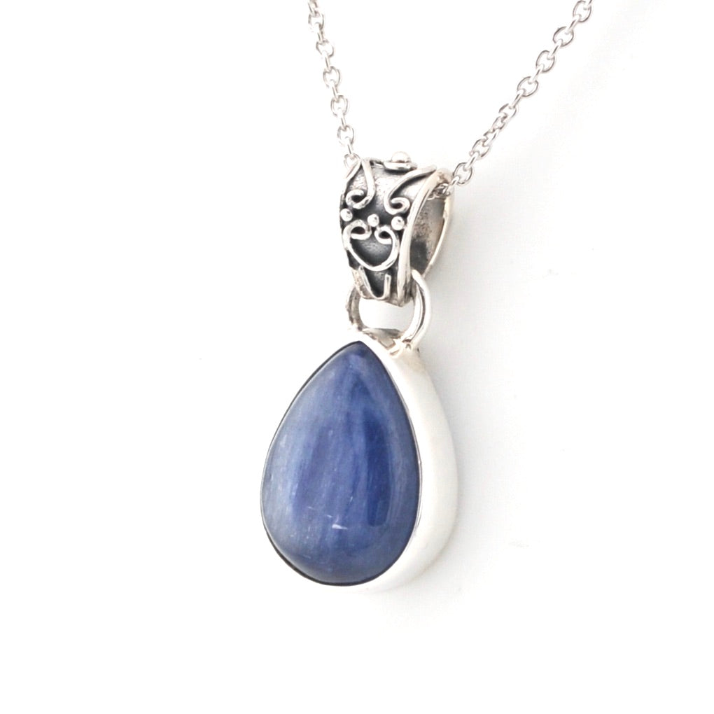 Teardrop-shaped blue kyanite pendant on a silver chain against a white background