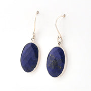 Pair of blue lapis oval earrings with silver on a white background